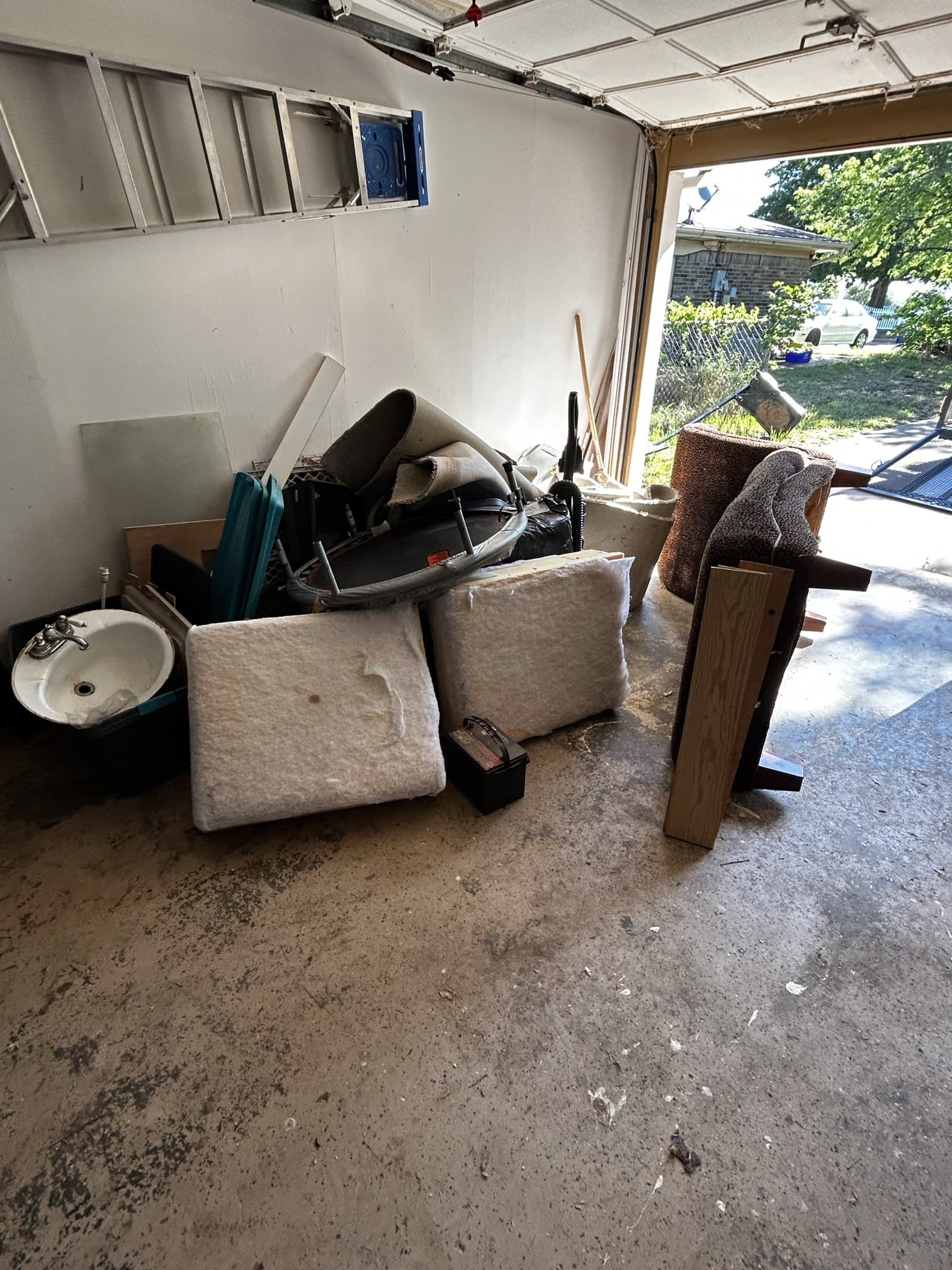Garage before junk removal — filled with old furniture, sink, carpet, and debris